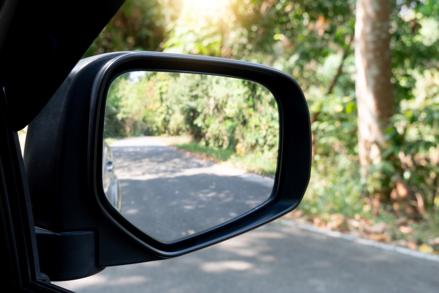 Rear view mirror of car on asphalt road background
